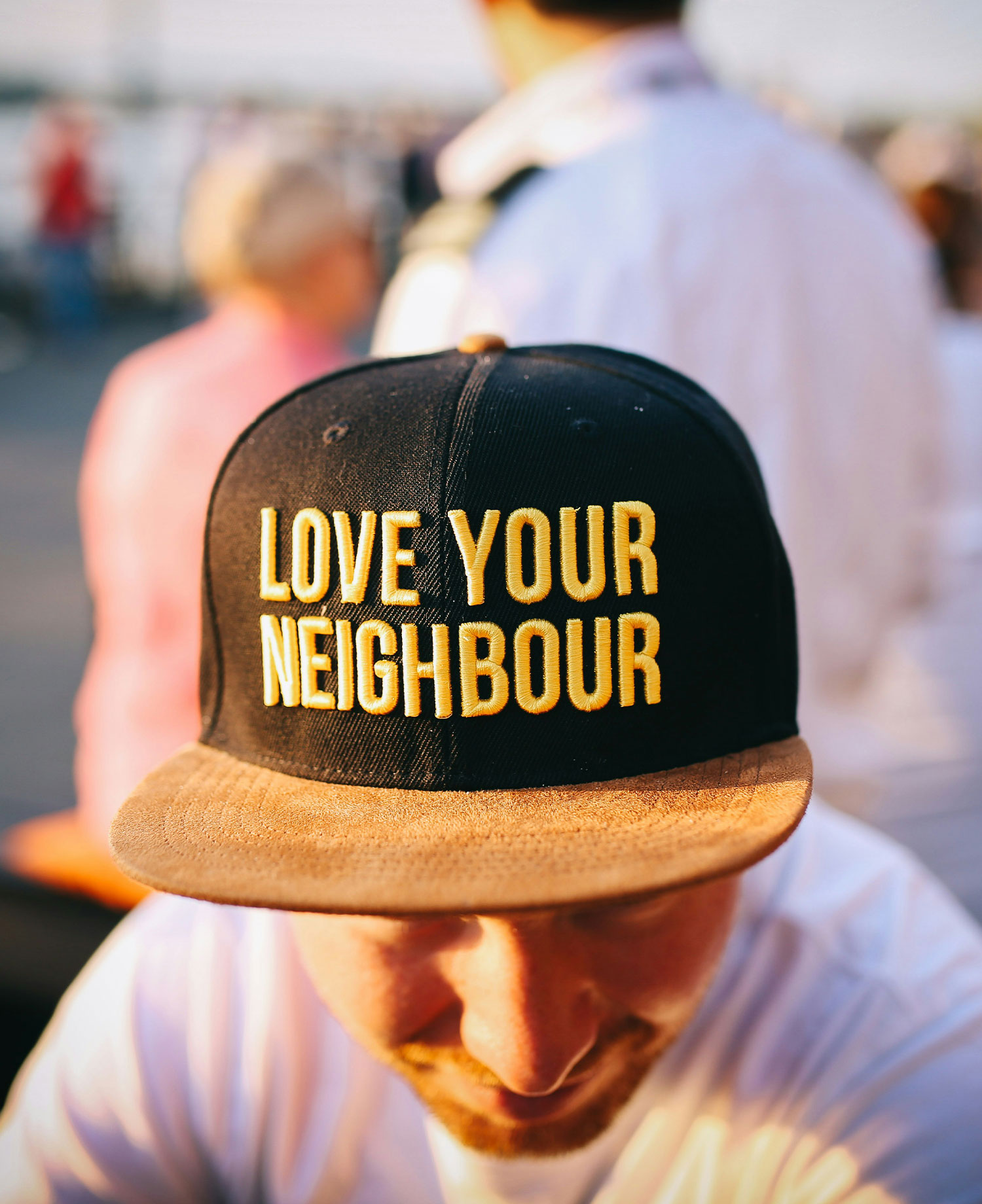 A man wearing a ball cap that says "Love Your Neighbour"