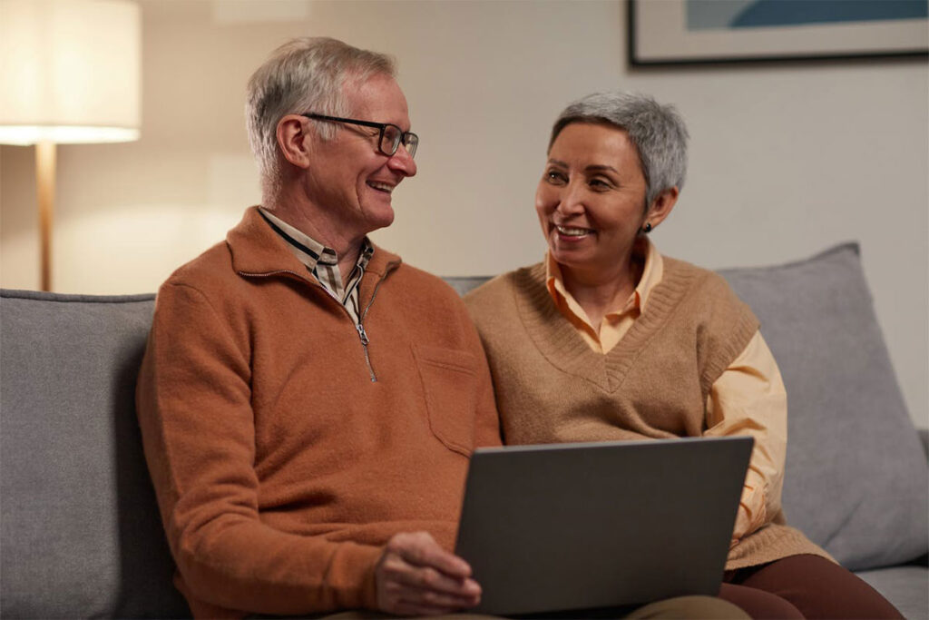 Two people look at something on a laptop together and smile