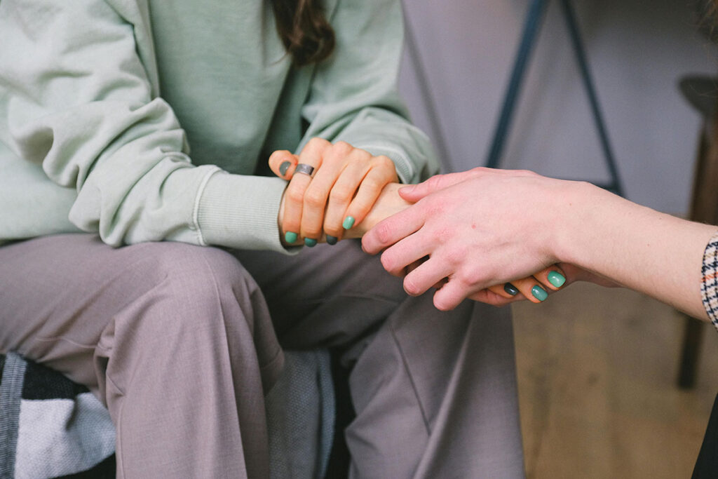 One person holding another person's hand in a supportive gesture
