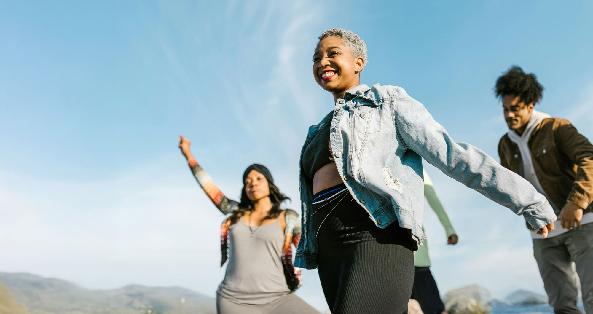 Three people are outside smiling and enjoying nice weather