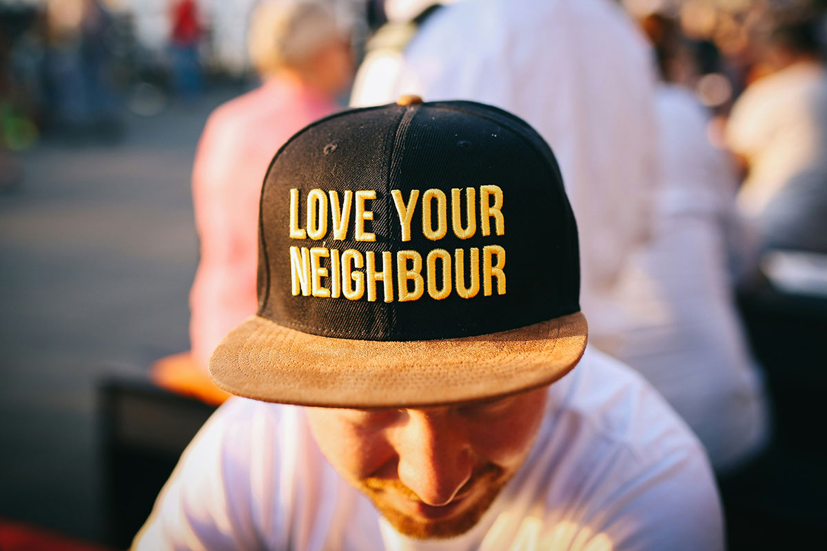 A man wears a hat that says "Love Your Neighbour"